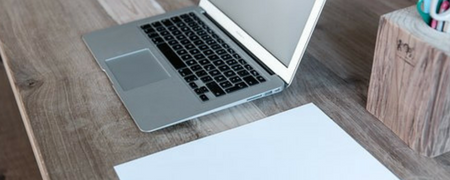 Öppen MacBook och papper på ett bord.