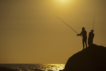 Två personer som fiskar med spö från en klippa.