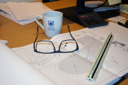 Glasögon och en kopp med Sotenäs kommuns logotype står vid en karta.