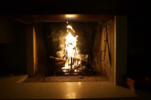 Eld brinner i en kamin i ett mörkt rum.