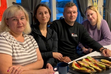 Fyra ukrainska flyktingar, tre kvinnor och en man, sitter vid ett bord på ett informationsmöte.