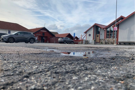 En vattenpöl på torget i Bovall med en fimp i förgrunden