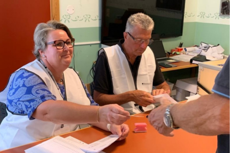 Kvinna och man tar emot röstsedlar i folkets hus Hunnebostrand under valet 2022