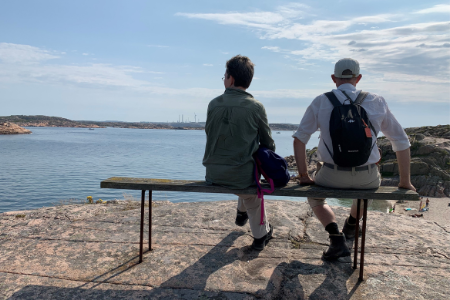 Ryggtavla på man och kvinna som sitter på en bänk och tittar ut över havet