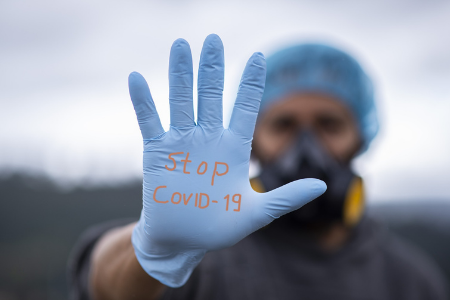 Sjukvårdspersonal står med handflatan uppsträckt och på den står det Stop Covid-19.