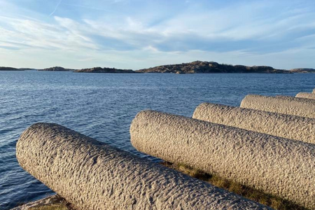 Liggande stenstavar sticker ut över havet vid Udden i Hunnebostrand
