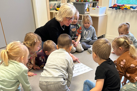 Förskolläraren Marianne Edén läser för barnen på golvet